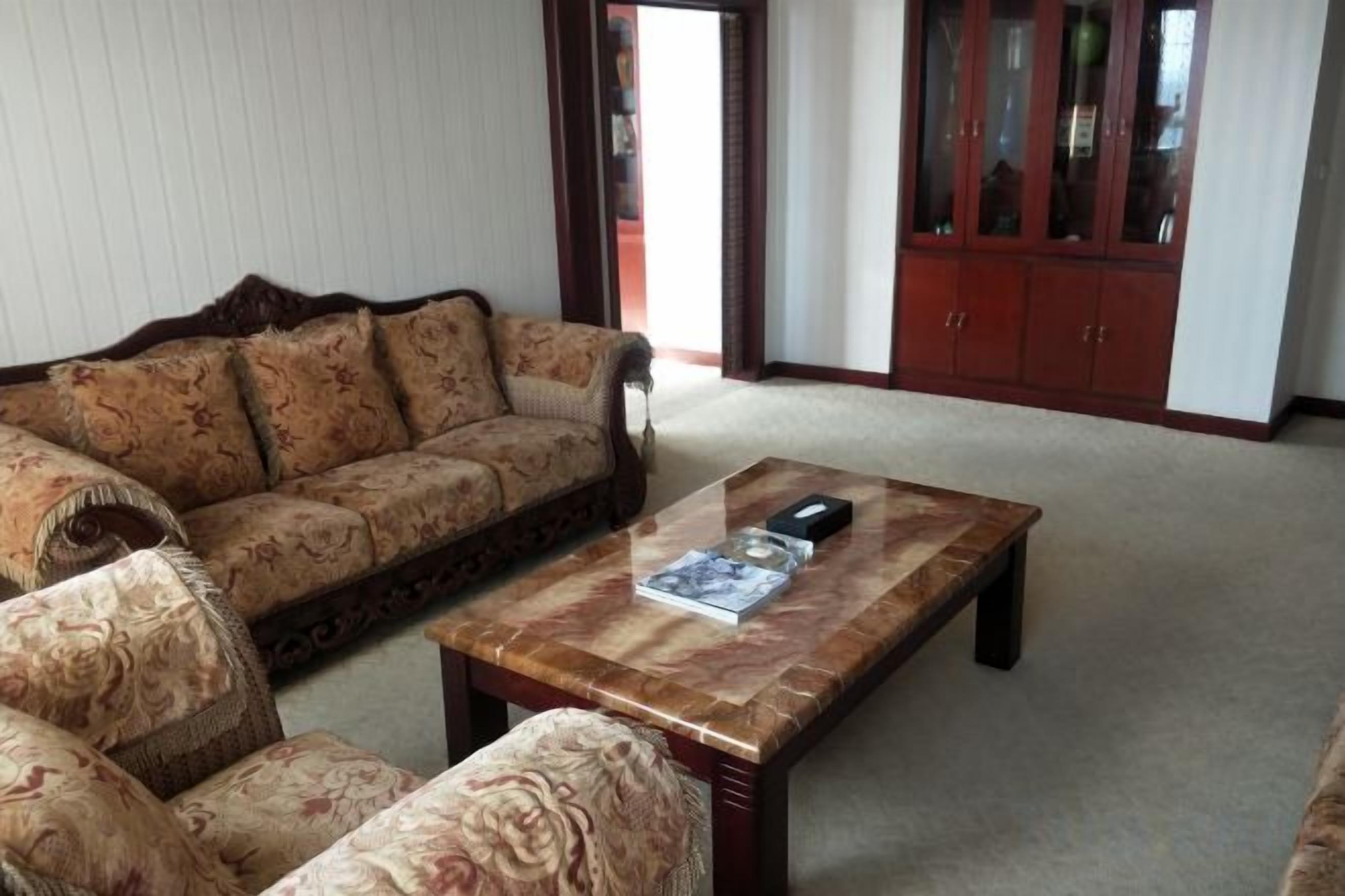 A living room with a sofa, armchairs, a coffee table, and a cabinet.