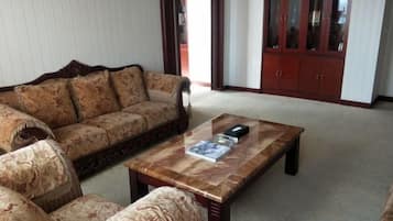A living room with a sofa, armchairs, a coffee table, and a cabinet.