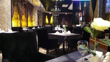 A restaurant interior with tables set for dining, chairs, and a chandelier.