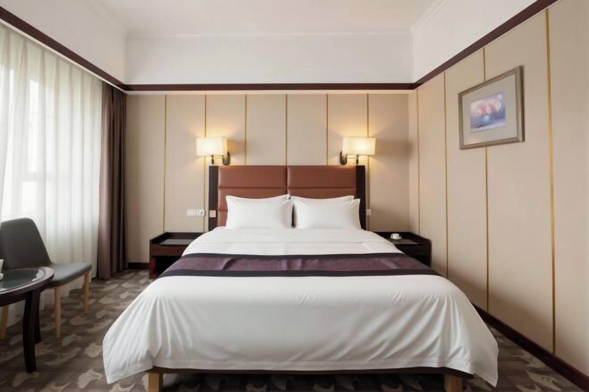 Una habitación de hotel con una cama grande, dos mesitas de noche, una silla y un escritorio.