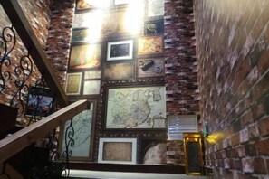 A staircase with a brick wall and framed pictures. - Grand View International Hotel (LIAOYANG)