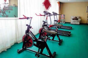 Une pièce équipée de vélos d’appartement, d’un tapis de course et d’une chaise.