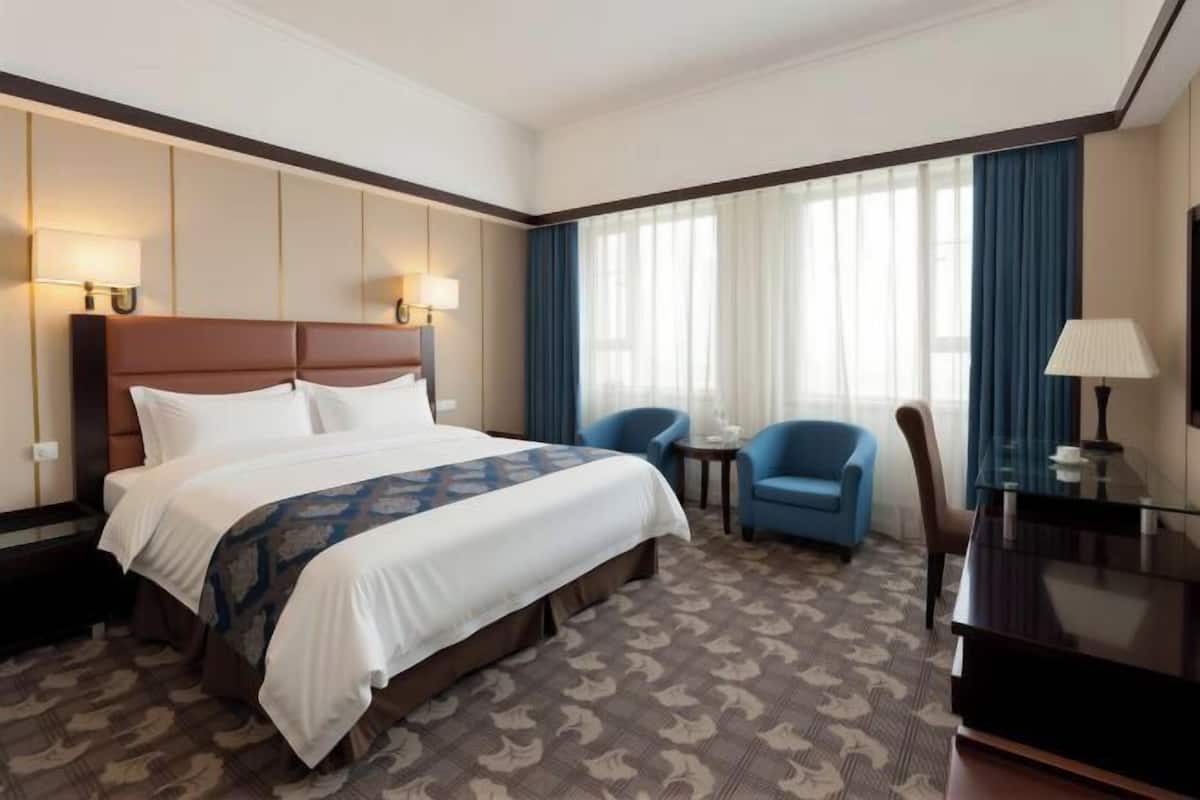 Una habitación de hotel con una cama grande, un escritorio, una silla y una mesita.
