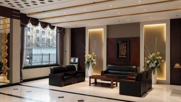 Una moderna hall d'albergo con reception, area relax e ampie finestre.