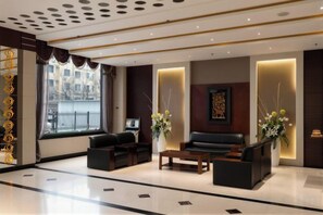 Un moderno vestíbulo de hotel con mostrador de recepción, zona de estar y ventanas amplias.