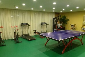 A room with a ping pong table, exercise bikes, and a treadmill. - Grand View International Hotel (LIAOYANG)