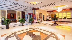 A hotel lobby with a geometric patterned floor, a reception desk, and potted plants. - Grand View International Hotel (LIAOYANG)