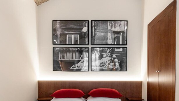 A bedroom with a bed, a wooden wardrobe, and three framed pictures on the wall. - Annunziata Guesthouse, Centro Storico (Naples)