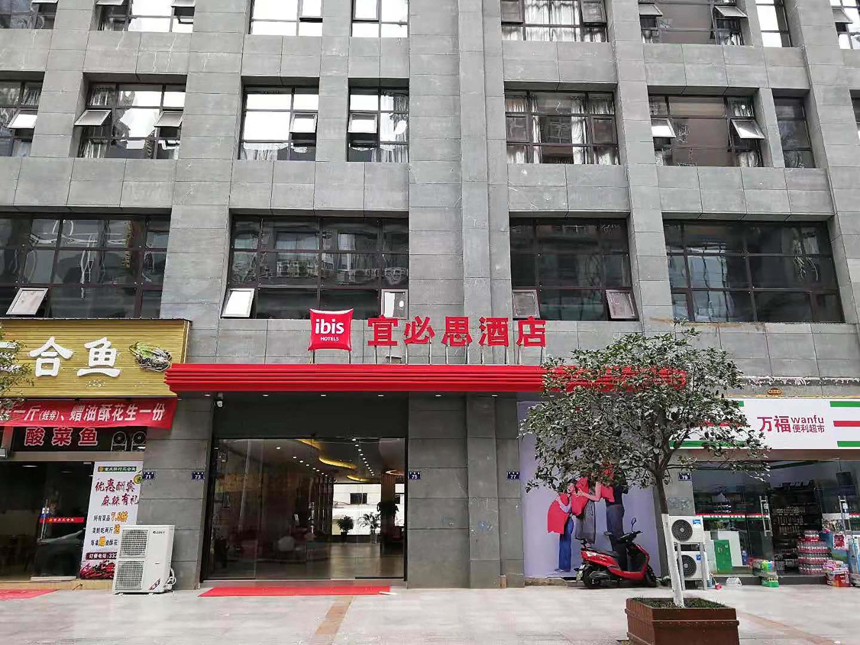 Un hotel con toldo rojo y señalización en caracteres chinos.