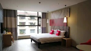 Moderni hotellihuone, jossa on suuri sänky, yöpöydät, työpöytä ja tuoli.
