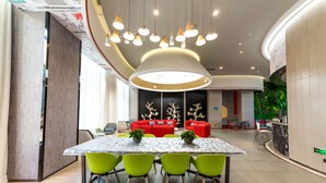Un comedor moderno con una mesa redonda, sillas verdes y un sofá rojo al fondo.