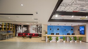 A modern reception area with a blue wall, a red sofa, and a wooden desk with two laptops. - Ibis Nanchang Bayi Museum Metro Station Hotel Hotel (Nanchang)