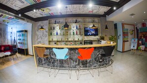 A bar area with a curved counter, two chairs, and a television screen. - Ibis Nanchang Bayi Museum Metro Station Hotel Hotel (Nanchang)