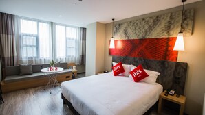 A modern hotel room with a large bed, a sofa bed, a small table with a plant, and a nightstand with a phone. - Ibis Nanchang Bayi Museum Metro Station Hotel Hotel (Nanchang)