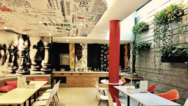 A modern restaurant with a central bar, white and red chairs, and a wall decorated with plants and text. - Ibis Nanchang Bayi Museum Metro Station Hotel Hotel (Nanchang)