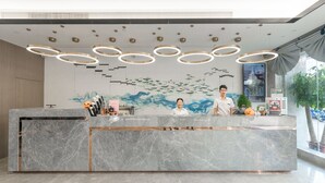 Balcão de recepção moderno com tampo de mármore, uma tela digital e um mural com pássaros e ondas.