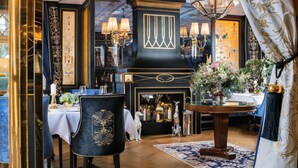 Comedor con decoración en negro y dorado, un candelabro y una mesa preparada para dos.