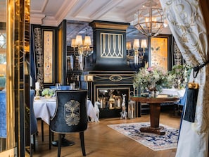 A dining area with a black and gold decor, a chandelier, and a table set for two.
