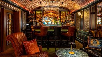 A bar area with leather chairs, a marble table, and a brick ceiling.