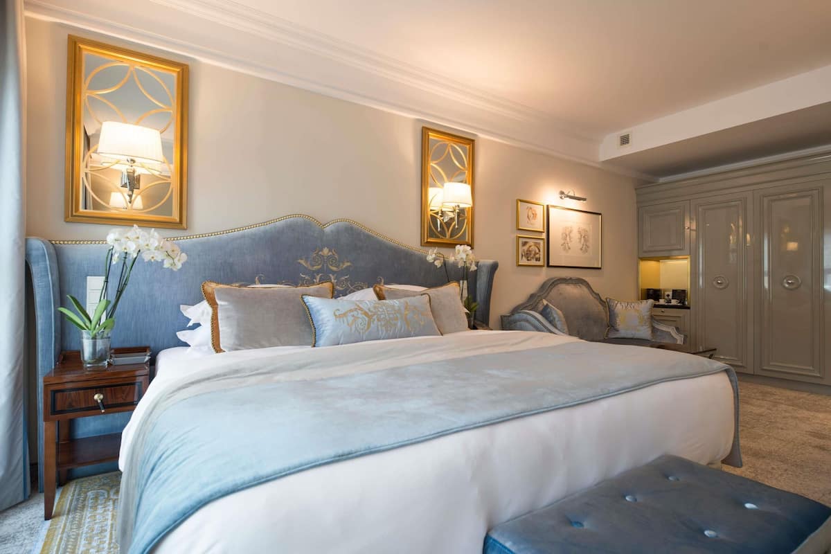 A bedroom with a large bed, a nightstand, a dresser, and a wardrobe.