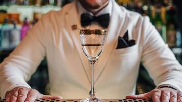Ein Barkeeper im weißen Anzug mit Fliege, der ein Cocktailglas hält.