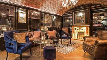 A luxurious lounge area with leather sofas, a round coffee table, and a fireplace.