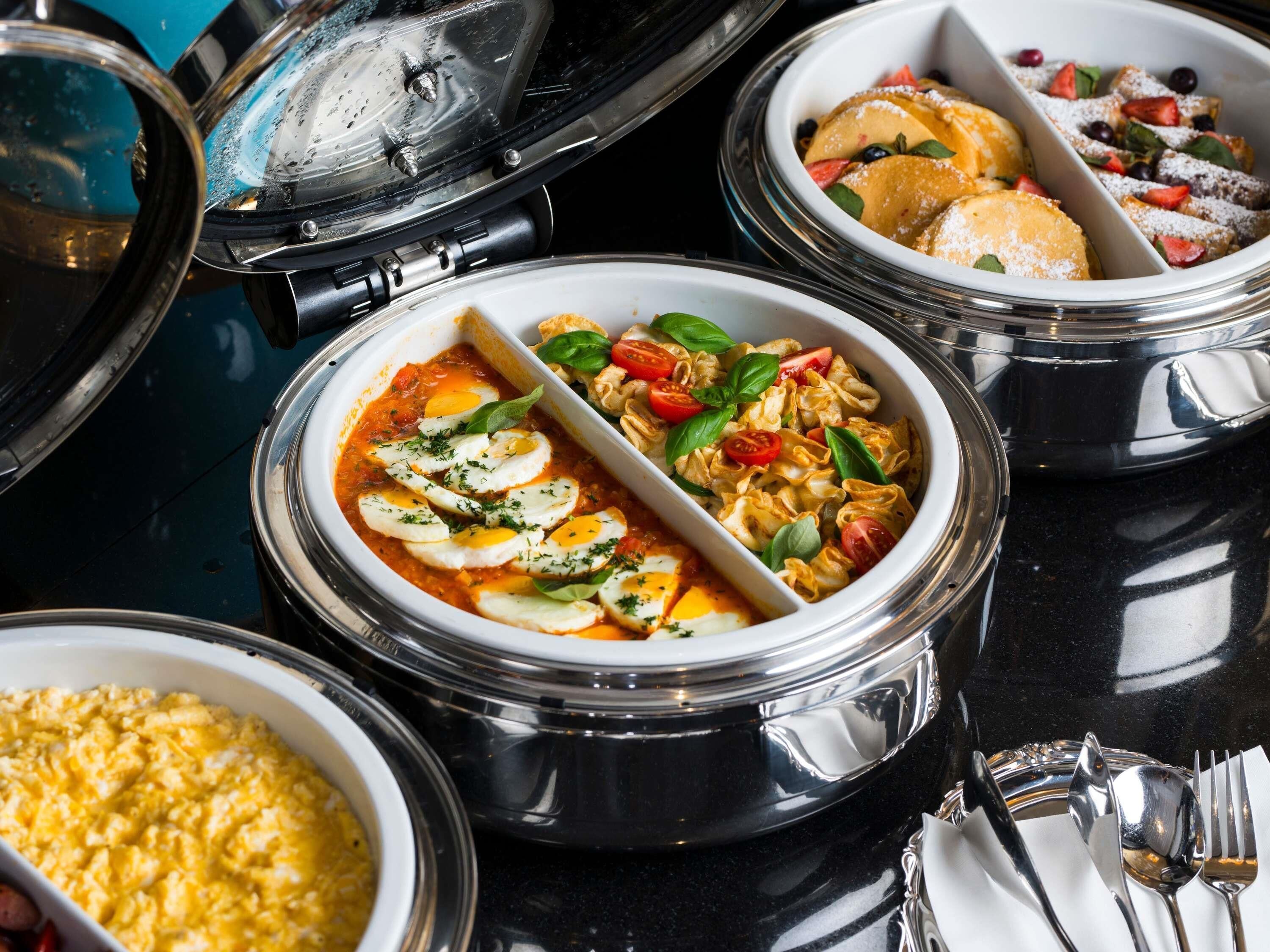 A variety of dishes in separate containers, including a bowl with eggs and tomatoes, another with pasta and vegetables, and a third with a dessert.