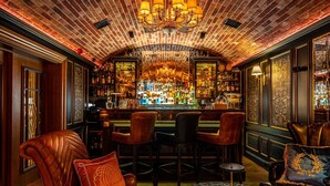 Zona de bar con sillones de cuero, una mesa de mármol y techo de ladrillo.