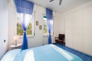 A bedroom with a bed, a chair, a small table with a lamp, and a wardrobe.