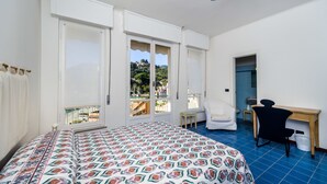 Une chambre à coucher avec un lit, un bureau, une chaise et une vue sur un balcon.