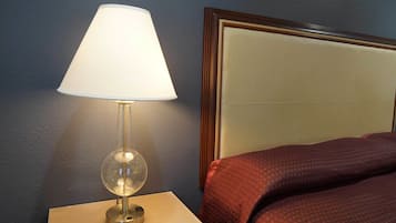 A hotel room with a bedside lamp, a bed with a headboard, and a nightstand.