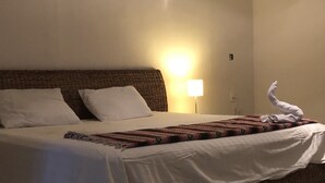 A hotel room with a bed, white linens, a patterned blanket, a lamp, and a towel on the bed. - Hostal Inn - Hostel (Playa del Carmen)