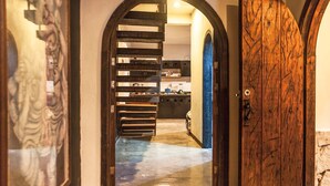 A hallway with a wooden door and an arched doorway leading to a kitchen area. - Hostal Inn - Hostel (Playa del Carmen)