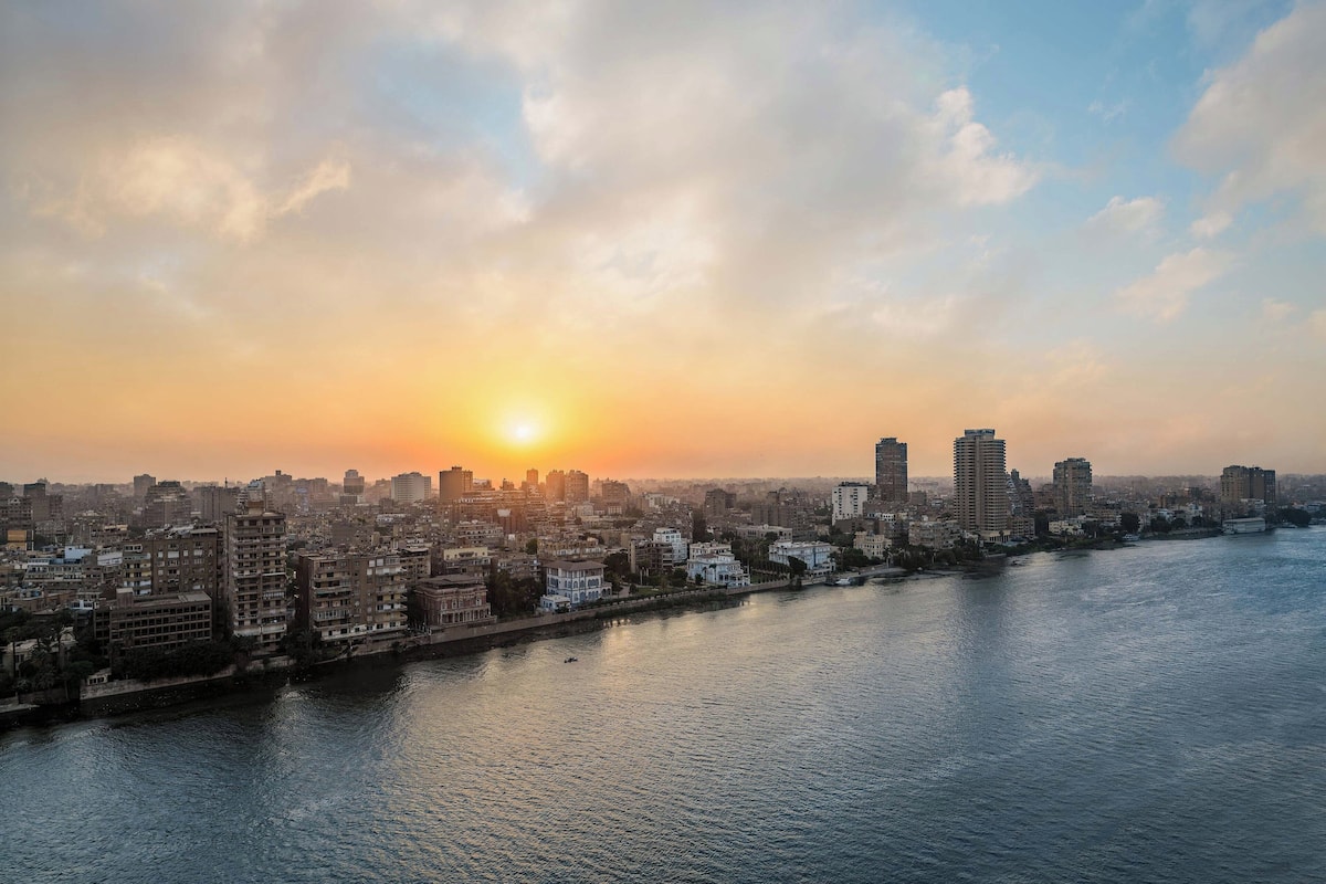 Un paisaje urbano con un río, edificios y un atardecer.