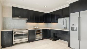 Uma cozinha moderna com armários escuros, eletrodomésticos de aço inoxidável e painel de azulejos.
