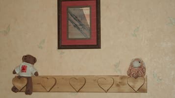 A wall with a framed picture, a shelf with heart-shaped decorations, and a teddy bear and a bird figurine.