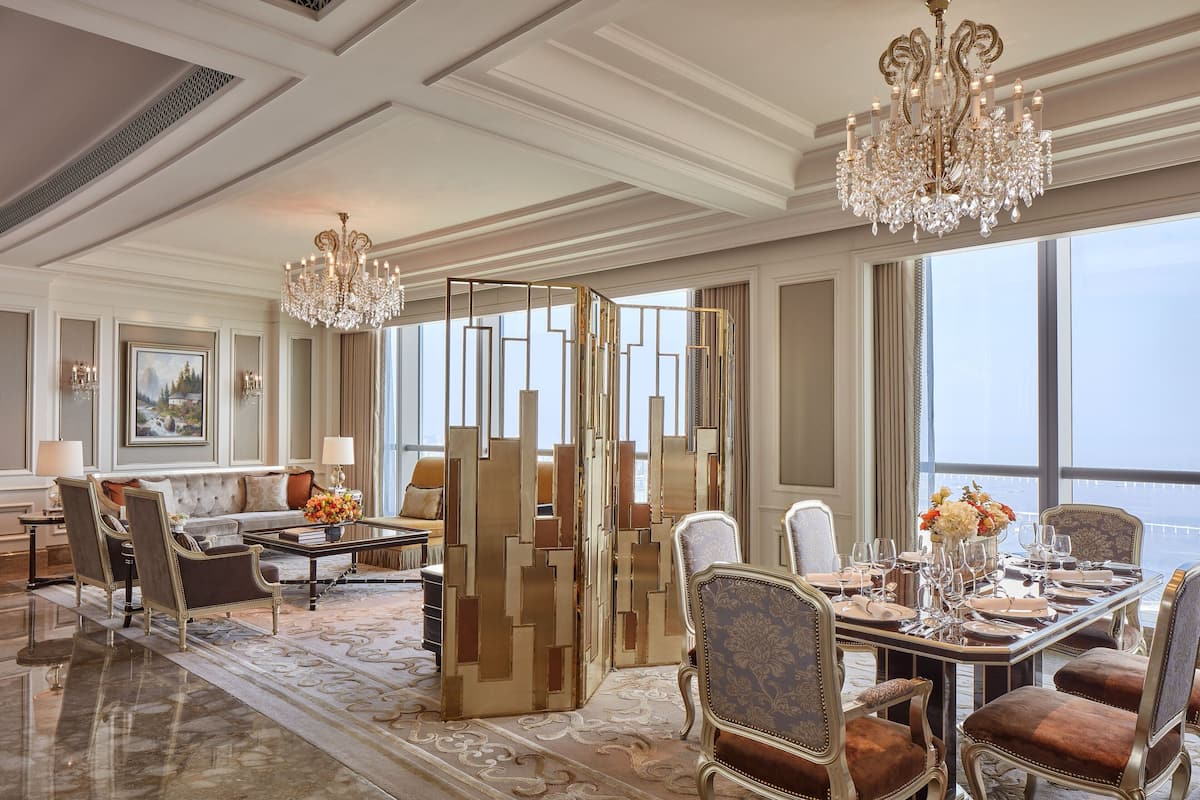 Un lobby de hotel lujoso con una gran araña, muebles elegantes y un amplio ventanal con vistas a la ciudad.