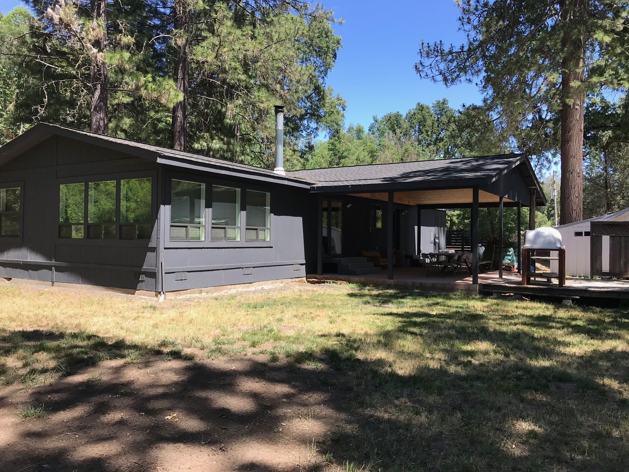 A modern house with a covered patio, a chimney, and a barbecue grill.