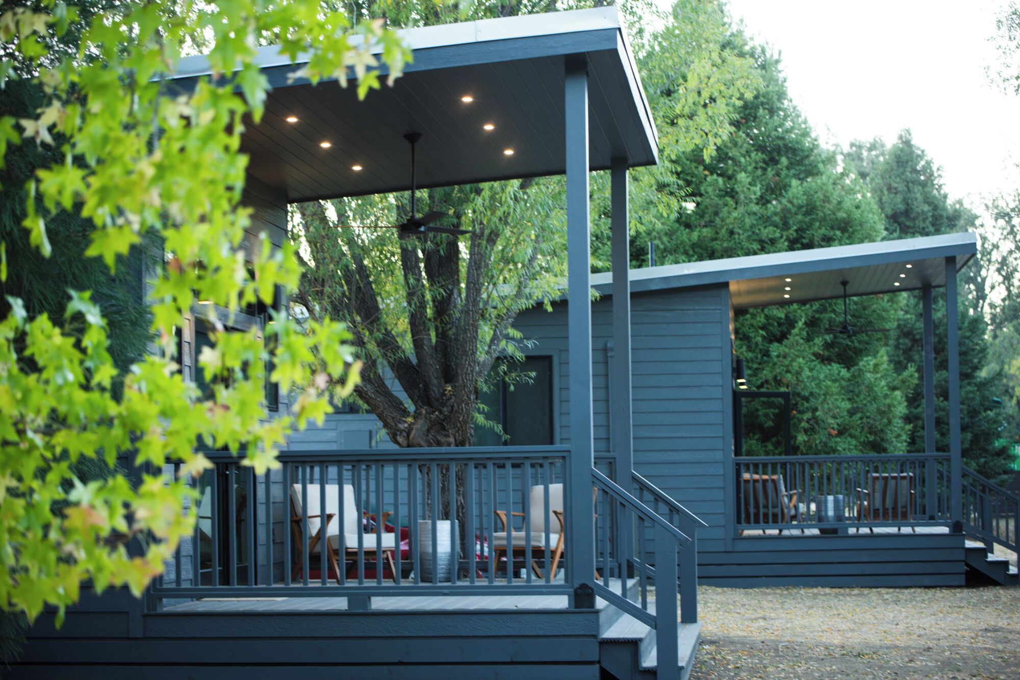 Een modern terras buiten, met een leuning, een overdekte zithoek en een trap naar een hoger niveau.