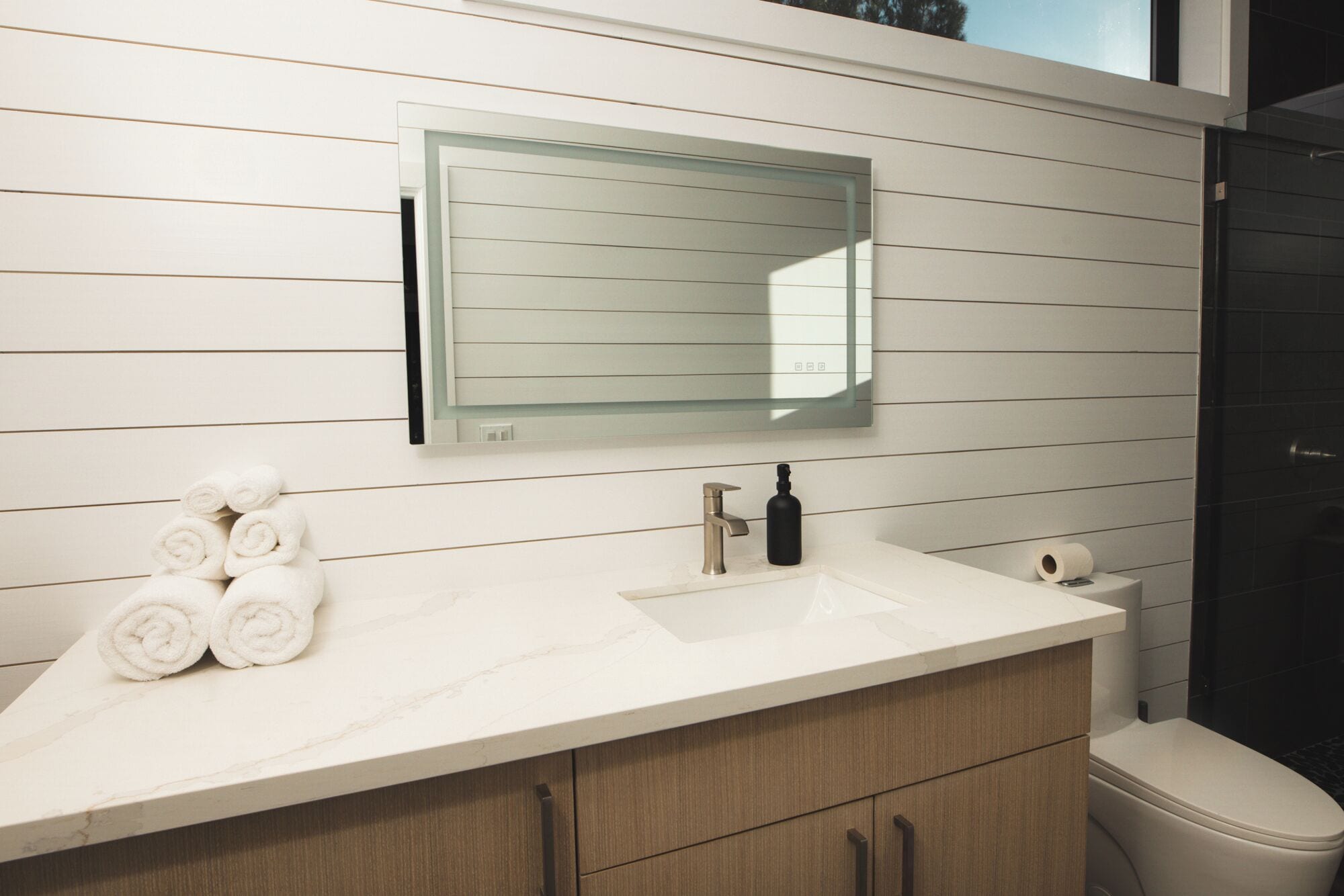 A bathroom with a white marble sink, a mirror, and a toilet.