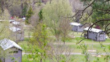 Une zone rurale avec plusieurs petites cabanes et un grand arbre au premier plan.
