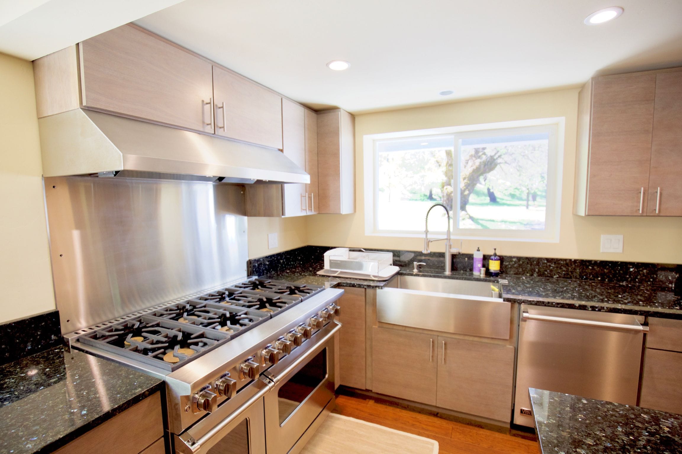 Una cocina moderna con electrodomésticos de acero inoxidable, armarios de madera y un ventanal que proporciona luz natural.