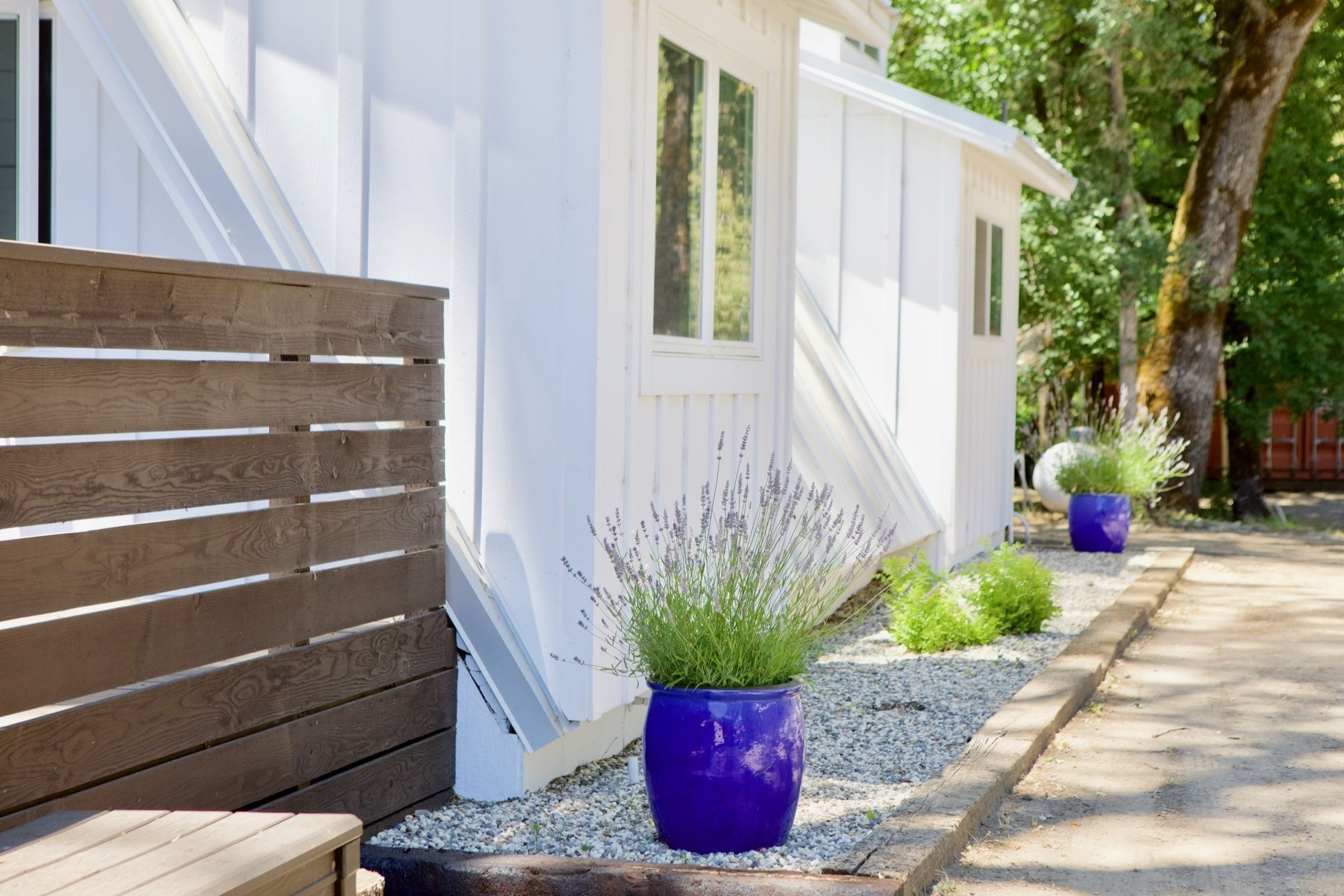 A row of white mobile homes with a wooden fence and gravel pathway.