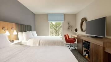 A hotel room with two beds, a TV, a desk, and a chair.