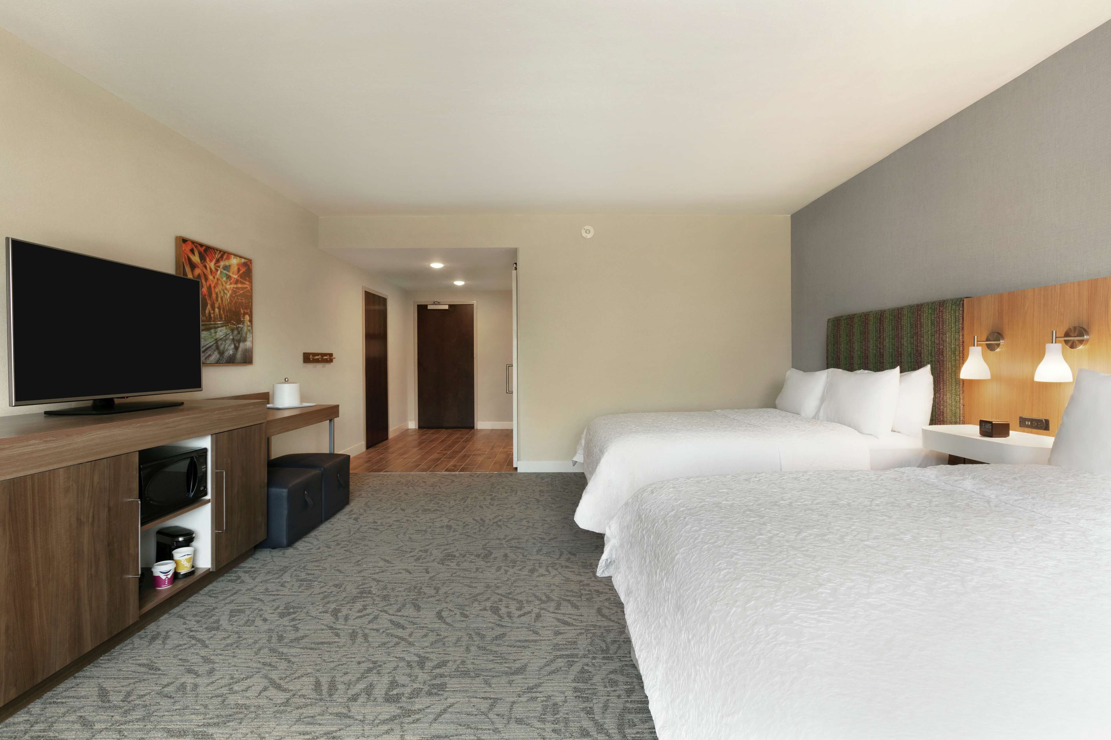 Habitación de hotel con dos camas, televisión, microondas y un pequeño rincón de descanso.