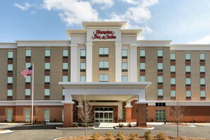 A Hampton Inn & Suites hotel with a modern facade, large windows, and a prominent American flag. - Hampton Inn & Suites Johns Creek (Johns Creek)
