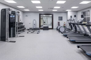 Uma academia com esteiras, halteres e aparelhos de musculação.
