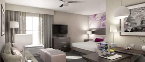 A hotel room with a bed, a desk with a laptop, a TV, a sofa, and a ceiling fan.