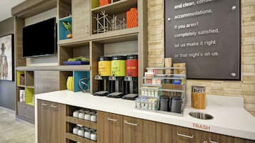 Un espace d’accueil d’hôtel comprenant un comptoir, un téléviseur et une poubelle.