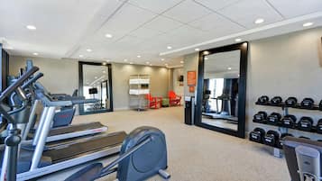 A gym with treadmills, an elliptical, and a rack of dumbbells.